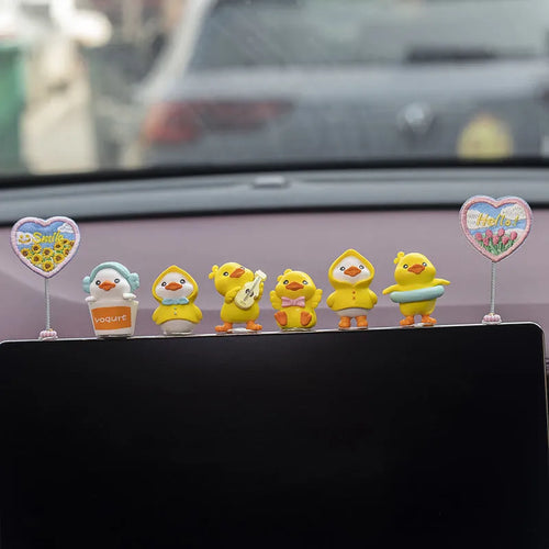 Set of six small cartoon duckling figures and one hello sign for car dashboard decoration.
