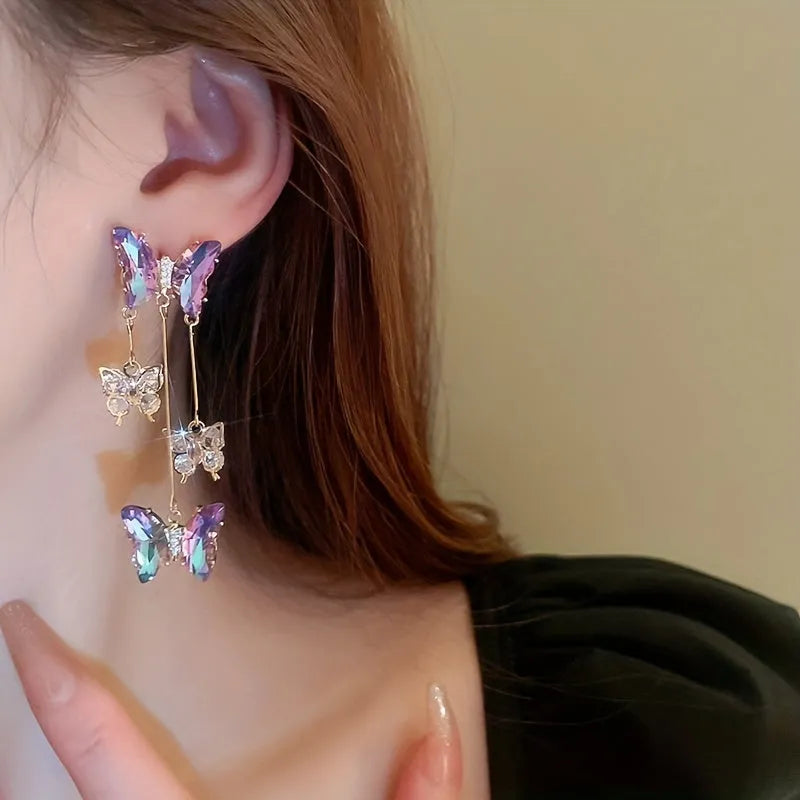 Silver needle style drop earrings with blue purple butterfly, crystals, and a tassel.