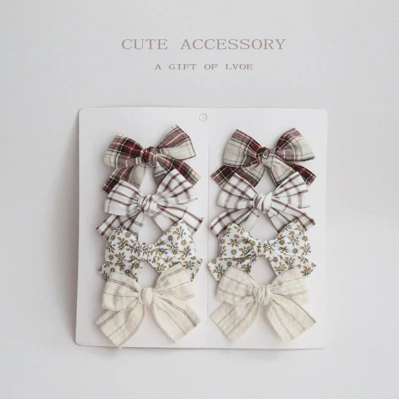 Set of eight fabric hairclips with dovetail bows in a chosen colour like beige grid dots or pink.