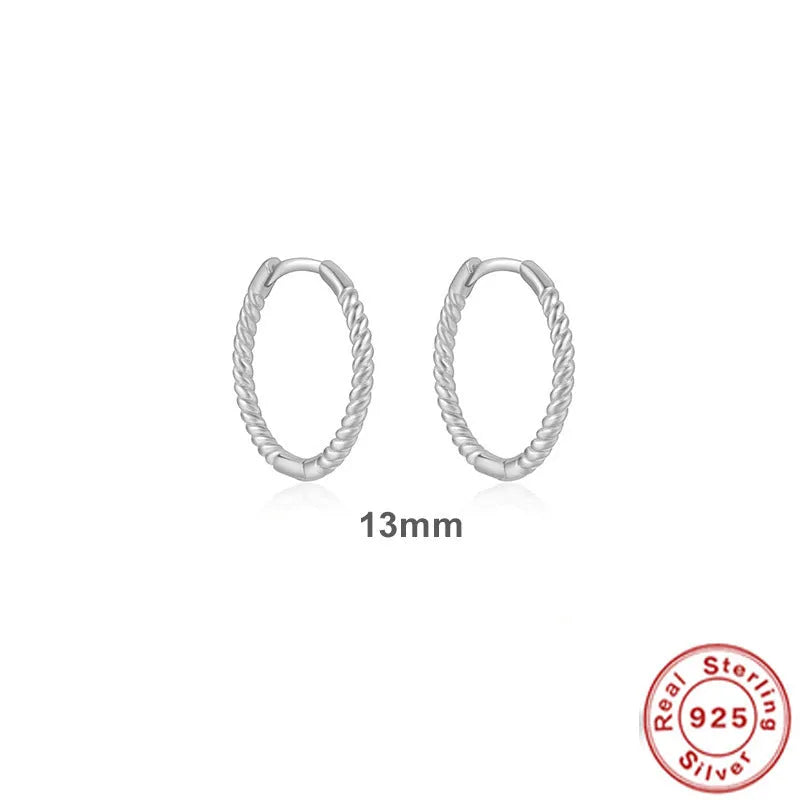 A pair of twisted sterling silver round earrings in a geometric design on a white background.