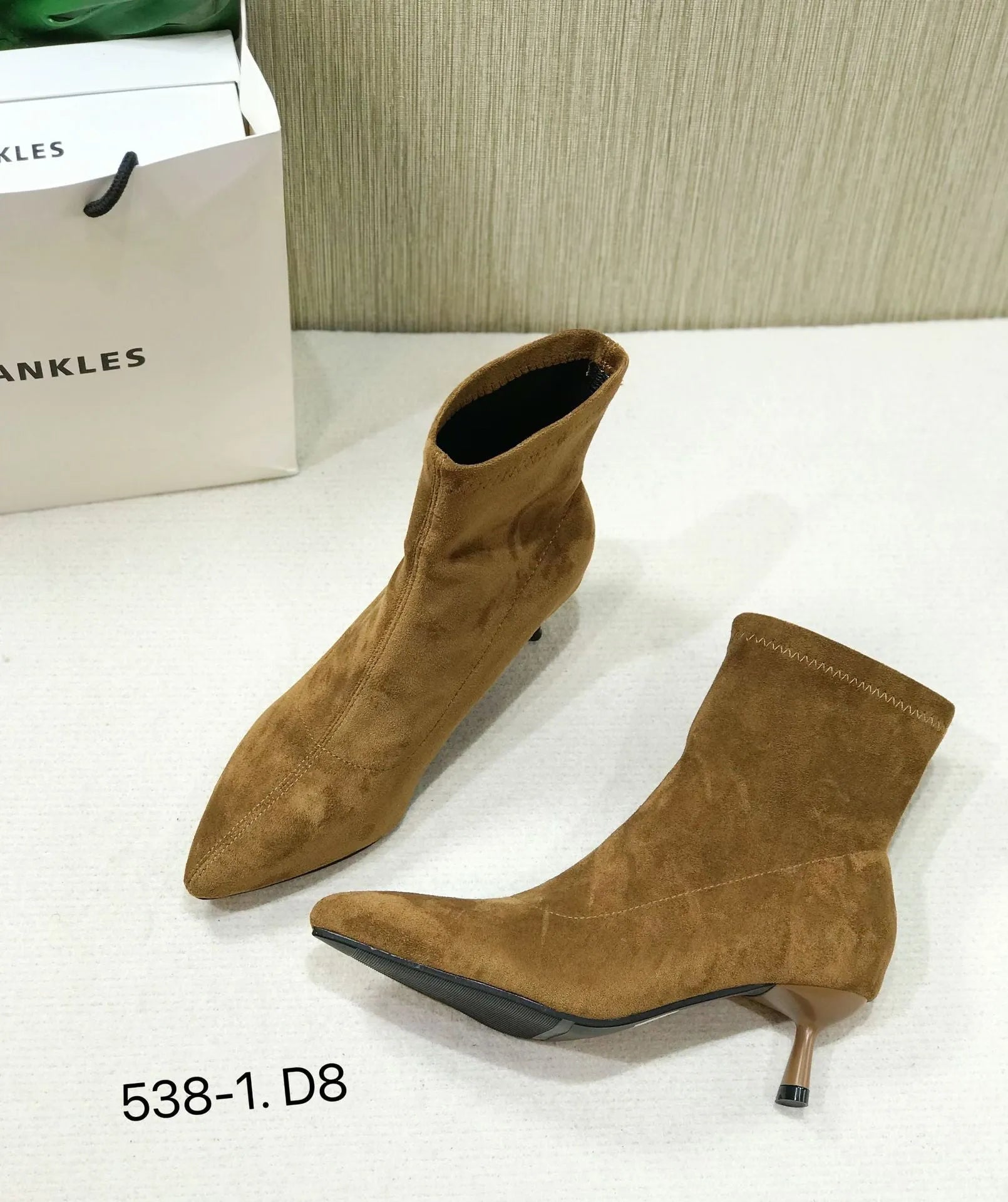 Black pointed toe stiletto ankle boots with a mid-calf sock length on a model.