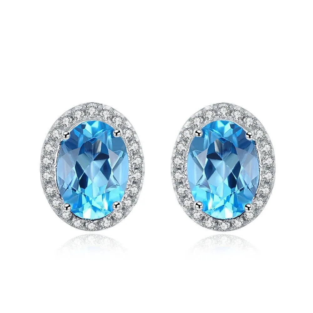 Women's sterling silver jewellery set with blue topaz gemstones in geometric design including earrings, ring, pendant, and necklace