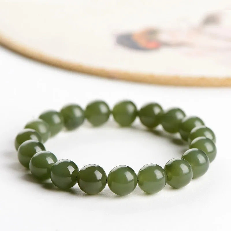 A close-up of a Hetian jade ball bracelet showing polished spherical beads in a clear stone colour, laid flat.