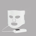 Black and white LED phototherapy face mask with controller for home skin light therapy.