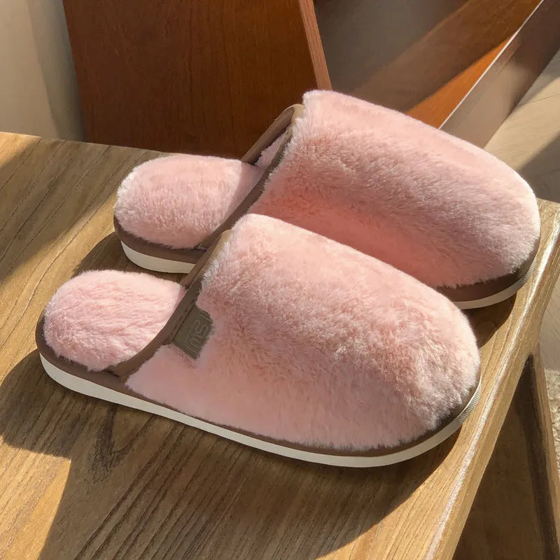 A pair of solid colour plush winter slippers with a non-slip PVC sole and car stitching detail.