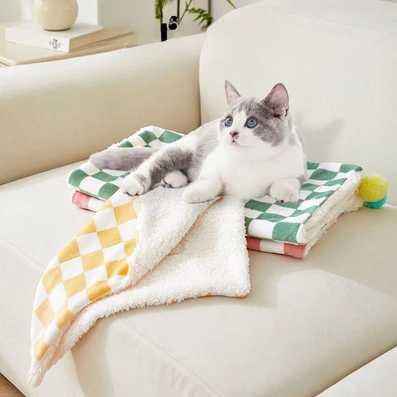 Plush pet blanket with plaid pattern and decorative fur ball in green colour