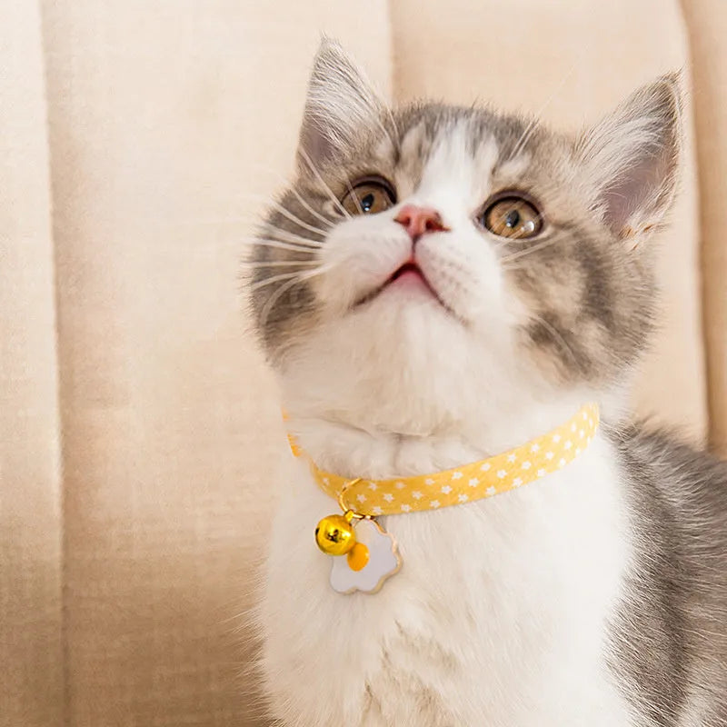 Green adjustable cat collar with a metal bell pendant and a matching bow tie on a white background.