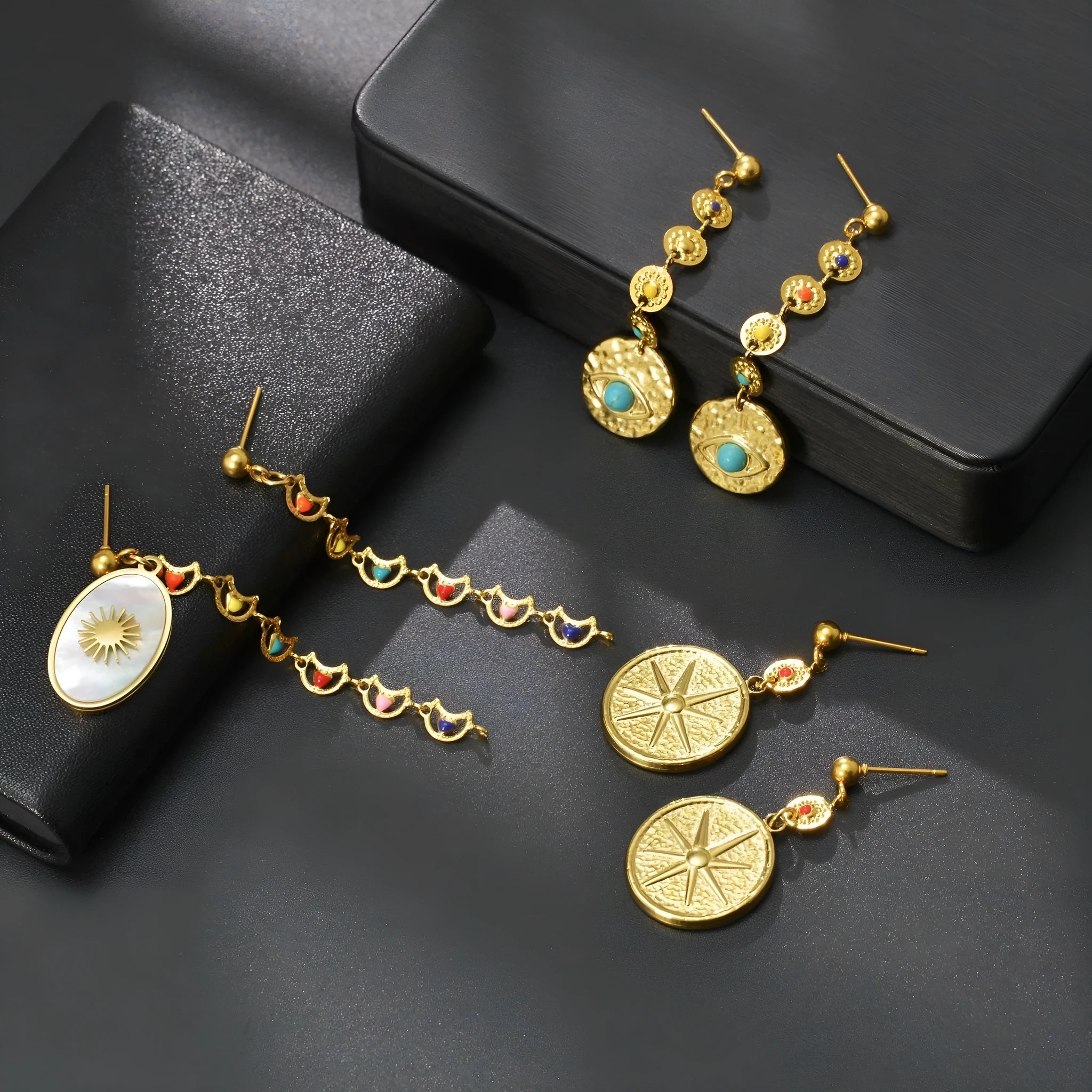 Three pairs of geometric stainless steel stud earrings showing star, eye, and sun designs