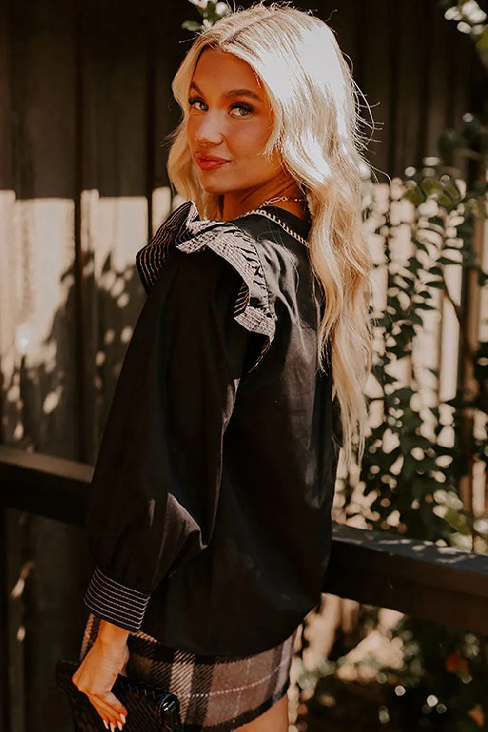 Black women's V-neck blouse with long ruffle-trimmed sleeves and contrast stitching