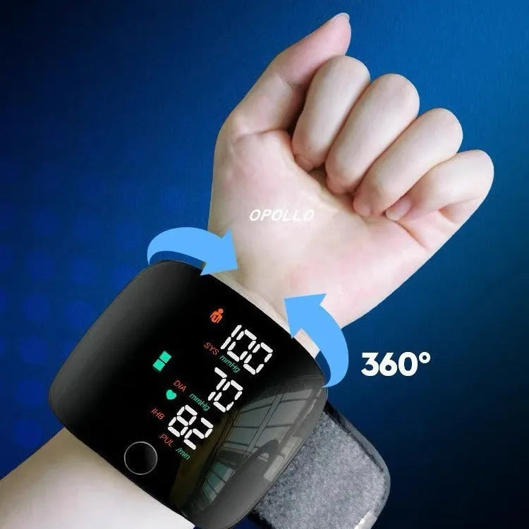 Black wrist blood pressure monitor with USB charging port on a table.
