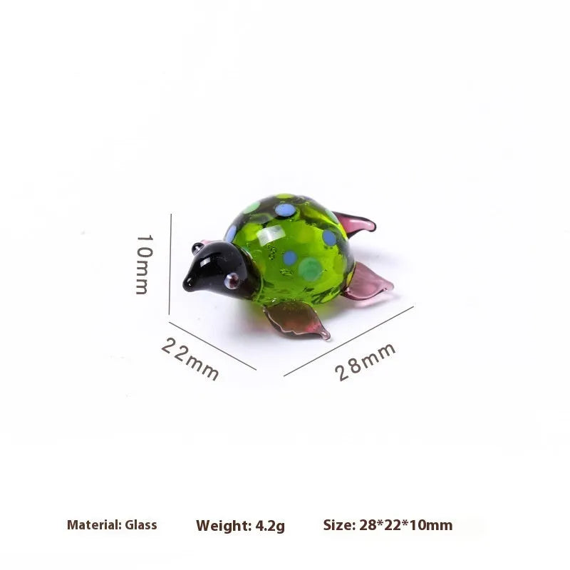 Geometric glass turtle ornament in a modern style with a coloured shell, displayed on a desktop.