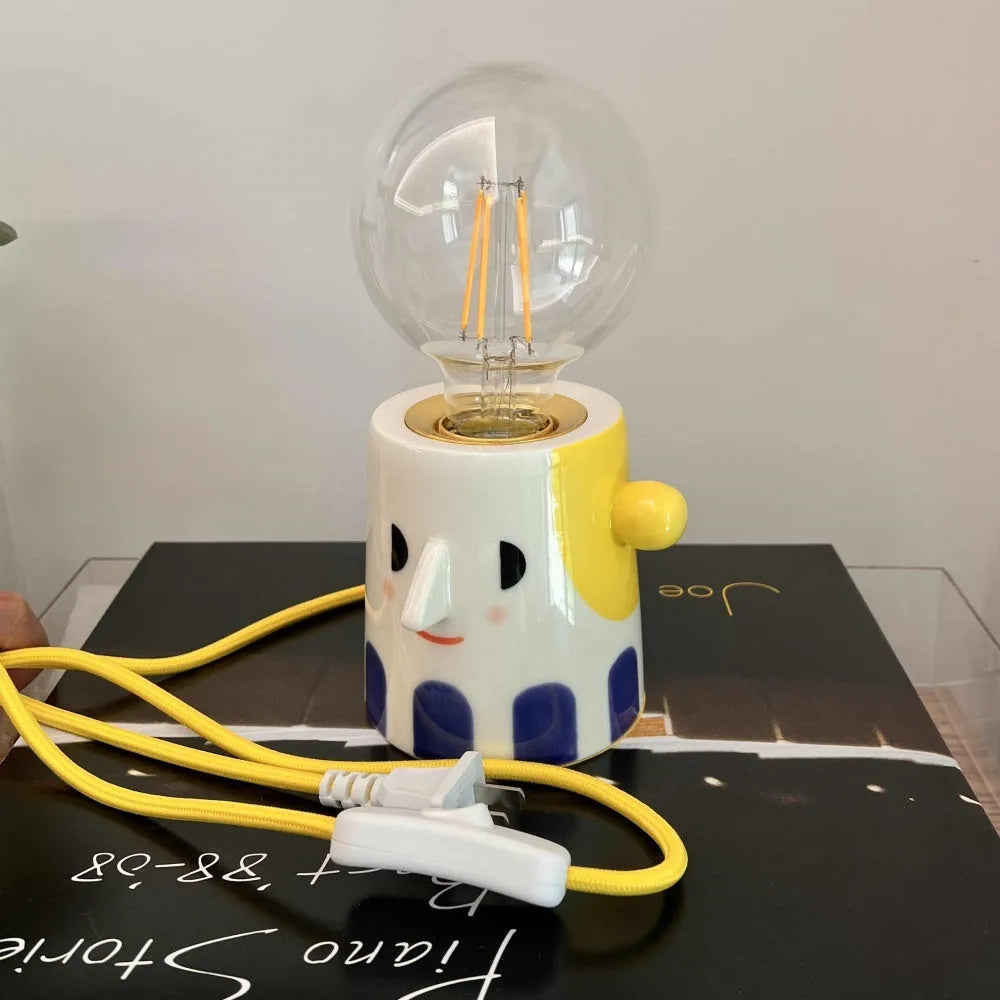 Handmade ceramic bedside lamp with a ball headlight design on a table.