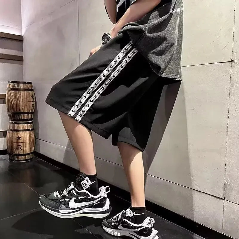Men's black loose-fit micro-elastic track pants shown in a casual standing pose.