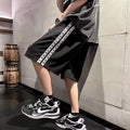 Men's black loose-fit micro-elastic track pants shown in a casual standing pose.