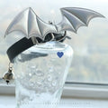 Small black patent leather dog collar with decorative devil wings design on a white background.