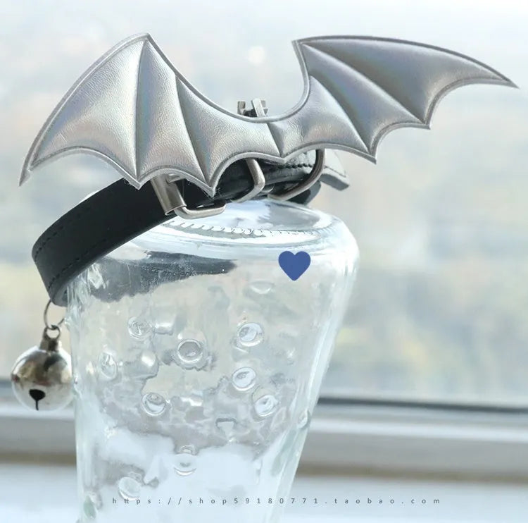 Small black patent leather dog collar with decorative devil wings design on a white background.