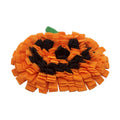 Orange pumpkin-shaped pet slow feeder mat on floor with scattered kibble