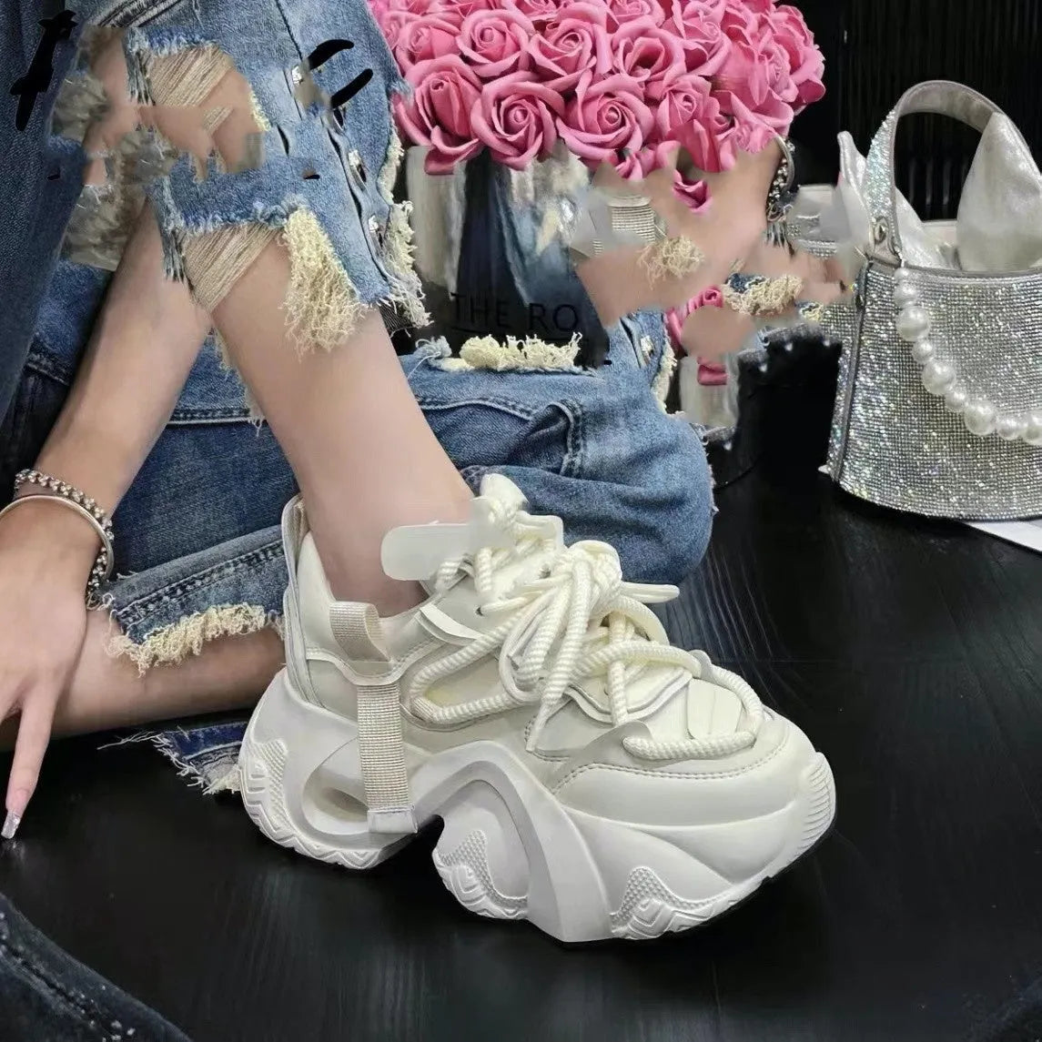 Women's white sneakers with cross straps and a hidden wedge heel on a wooden floor