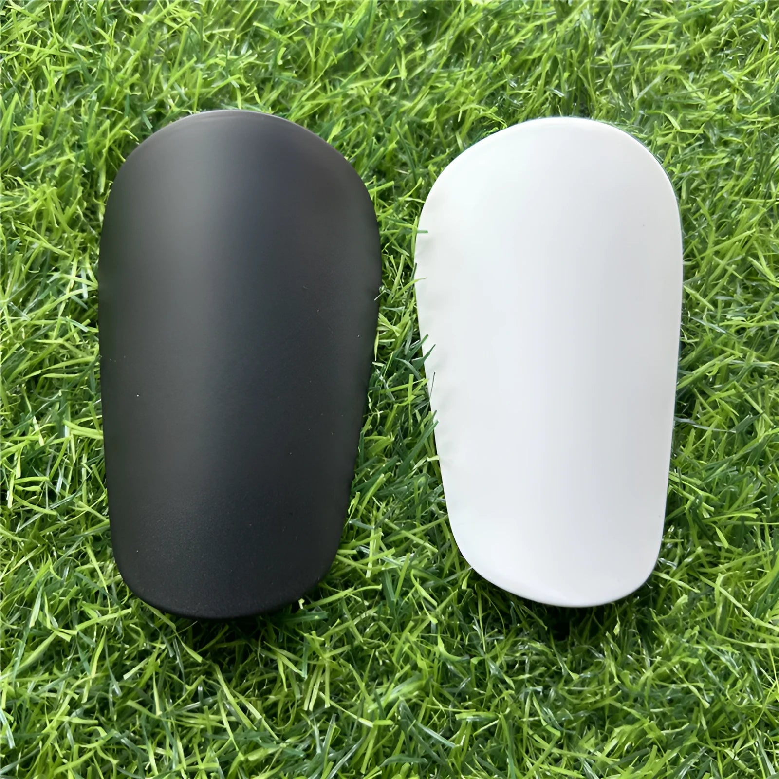 Extra small mini football shin guards in black and white plastic construction