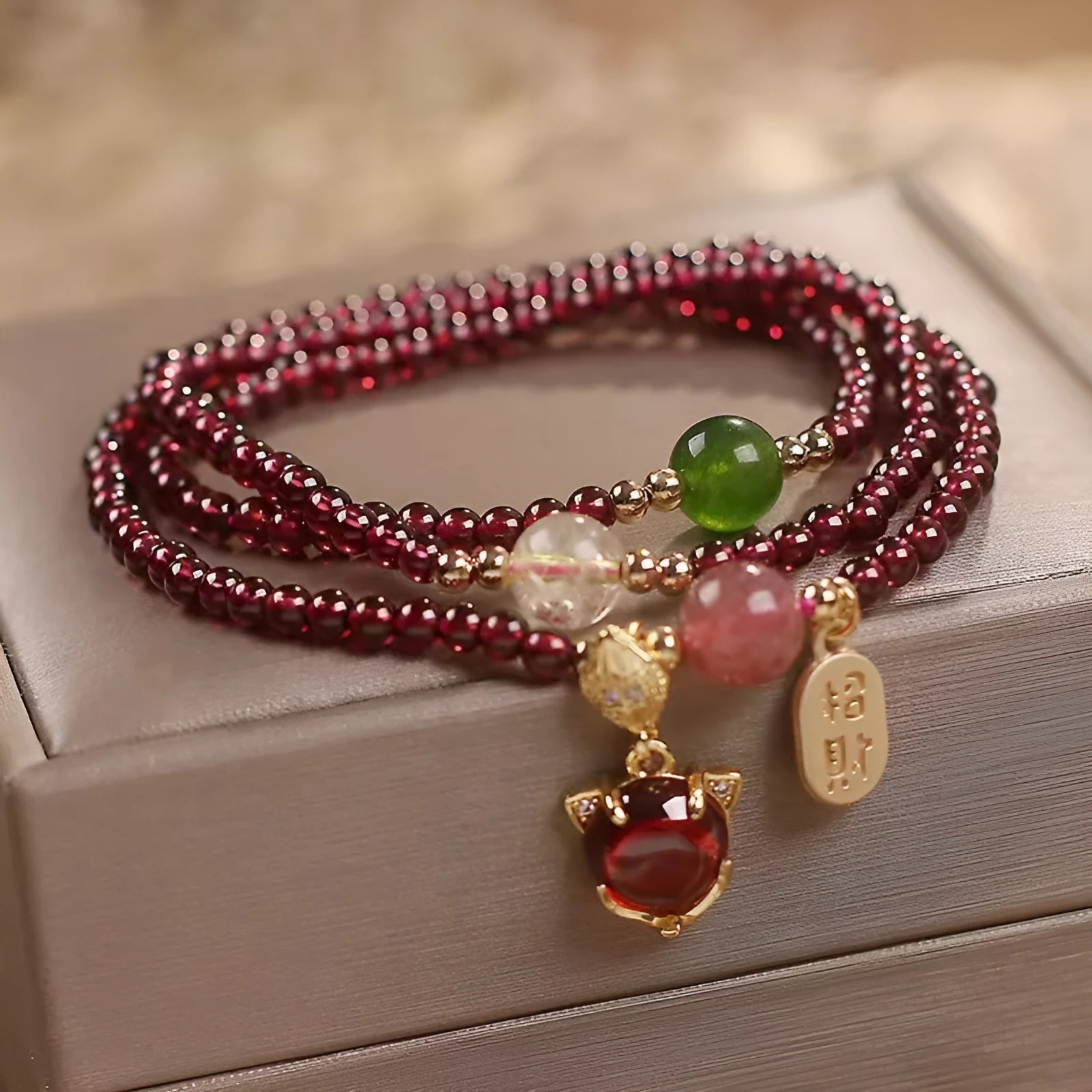 Purplish red garnet fox charm bracelet with adjustable rope on a wrist.