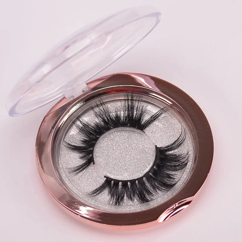 A pair of handmade 5D false eyelashes made from mink hair, shown with a double-headed brush and a hair cap.