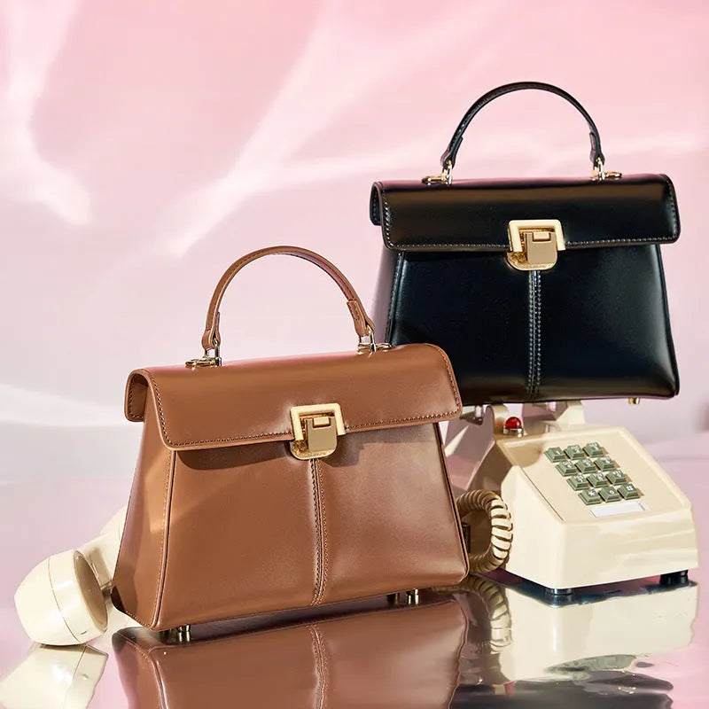 Women's black genuine leather shoulder bag with gold clasp closure showing interior compartments
