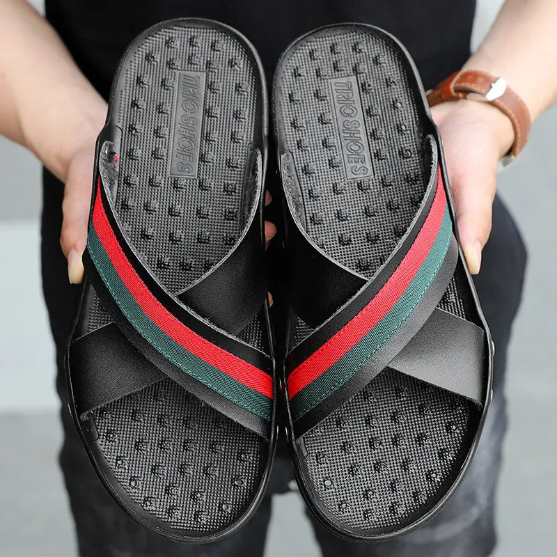 Men's white cowhide leather flip flops on a sandy beach background.