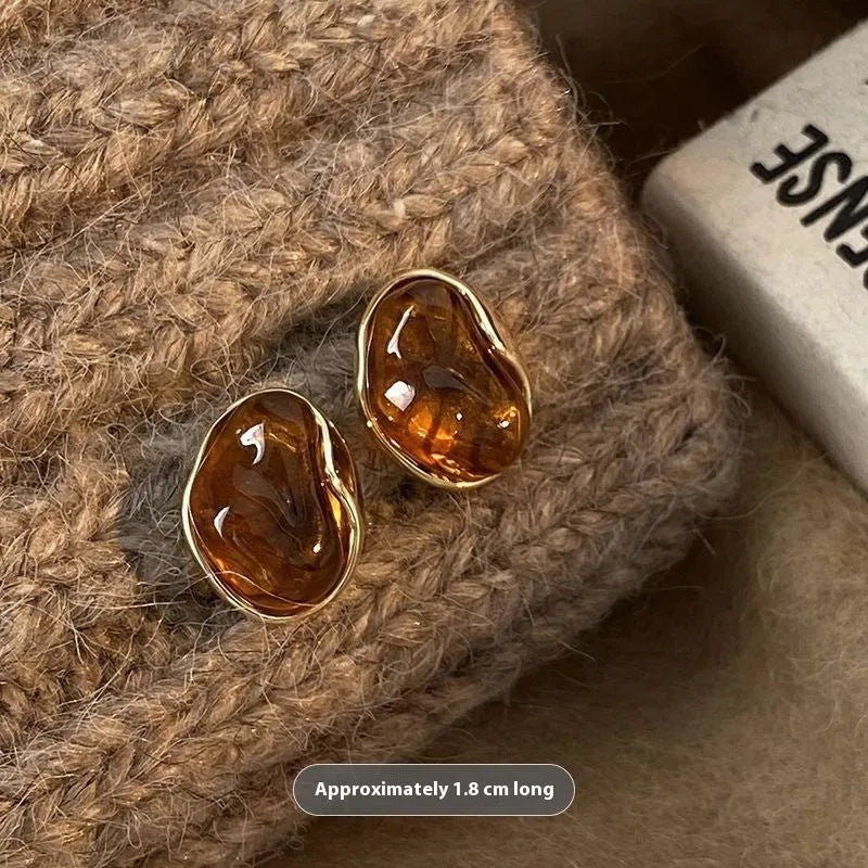 Handmade geometric earring set showing three styles: round piece, irregular amber, and water drop tigereye studs with tassels.