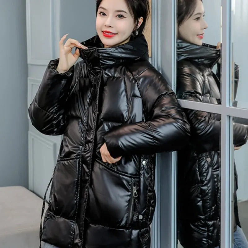 A green loose-fit hooded winter jacket for women on a hanger, showing long sleeves and thick insulation.