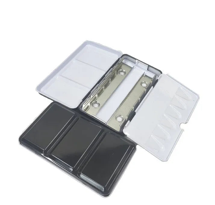 Square tinplate three-fold paint box for solid watercolours, shown open with empty slots.