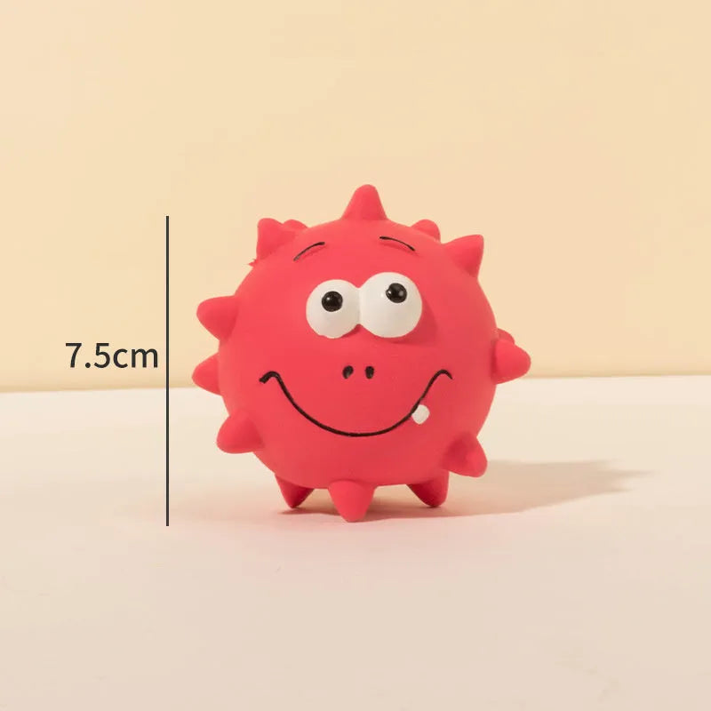 Set of four colourful latex squeaky dog balls with cute faces on a textured surface.