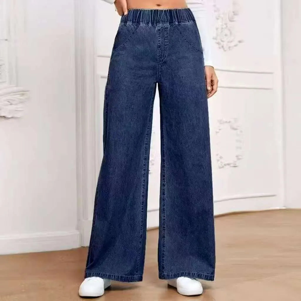 Light blue washed wide-leg denim trousers on a hanger, showing straight cut and zip front.