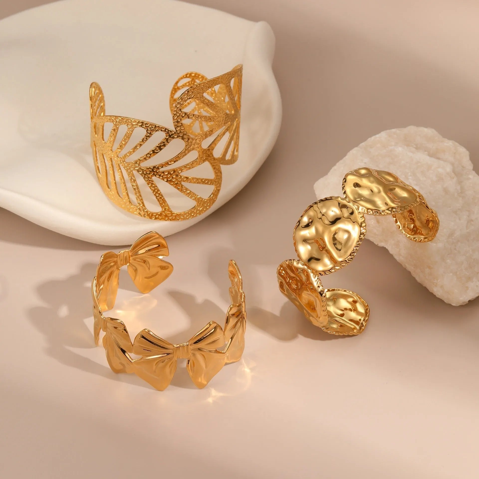 Gold stainless steel wristband with geometric leaf bow design on white background