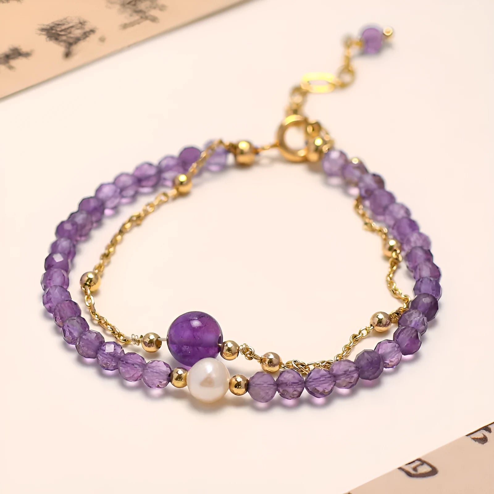 Close-up of a Chinese style women's bracelet with a diamond-shaped amethyst crystal on an electroplated chain.
