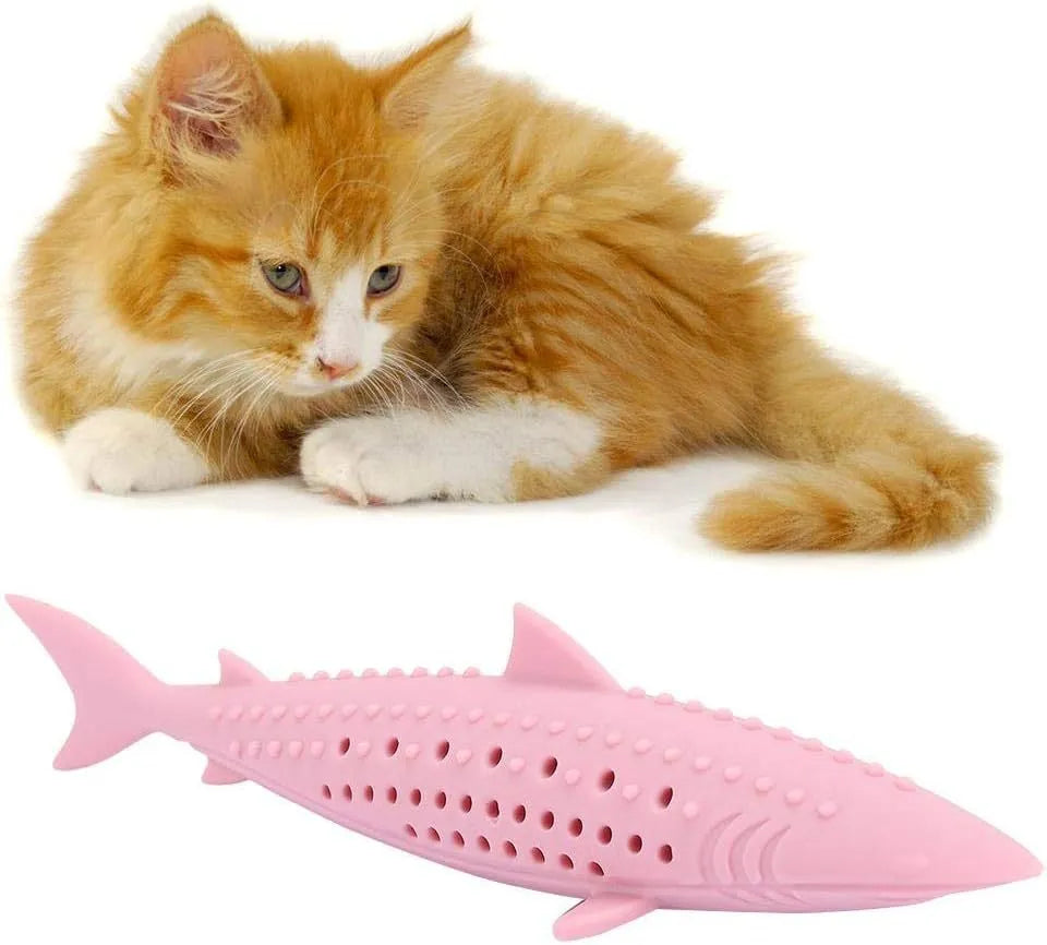 Green silicone fish-shaped cat chew toy with breathable side holes on wooden floor
