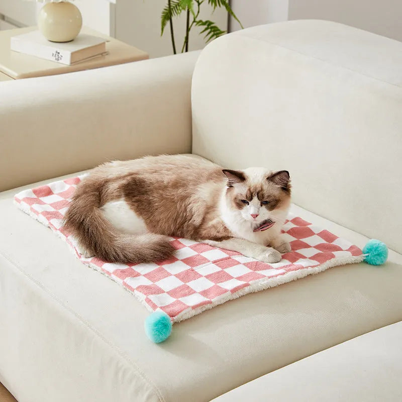 Plush pet blanket with plaid pattern and decorative fur ball in green colour