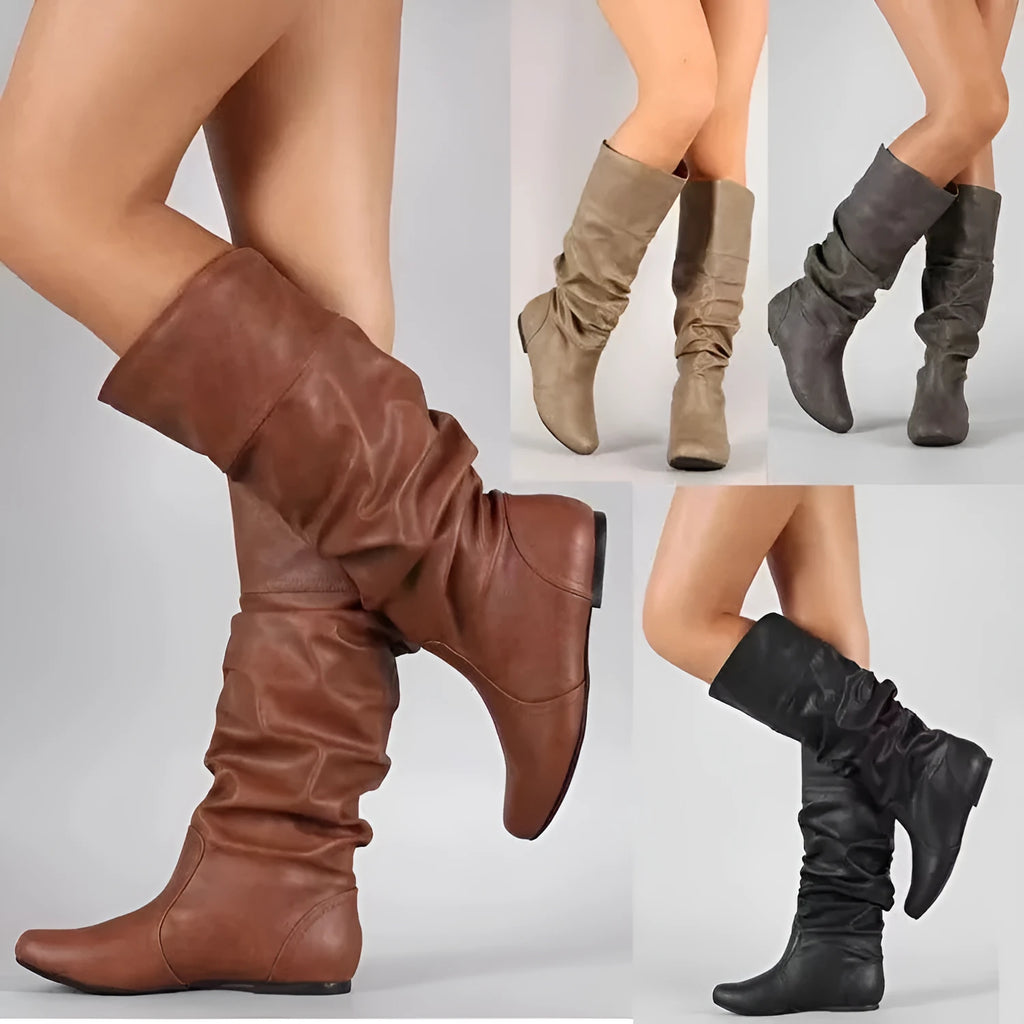Women's flat slip-on long boots with round toe in black, shown on a foot.