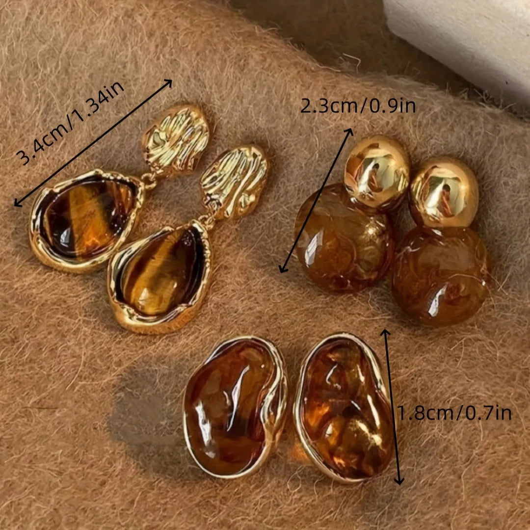 Handmade geometric earring set showing three styles: round piece, irregular amber, and water drop tigereye studs with tassels.