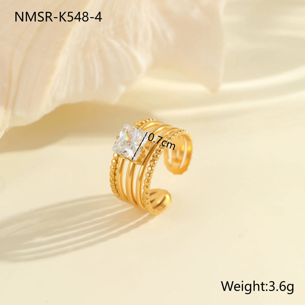 Gold inlaid zircon geometric heart and drop shape stainless steel ring on white background.
