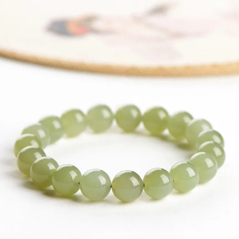 A close-up of a Hetian jade ball bracelet showing polished spherical beads in a clear stone colour, laid flat.