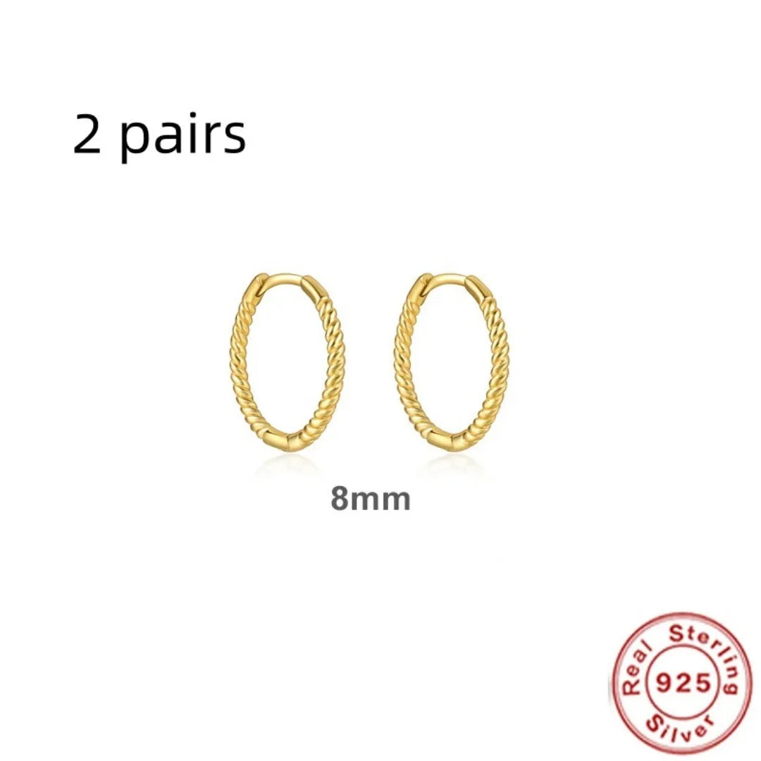 A pair of twisted sterling silver round earrings in a geometric design on a white background.