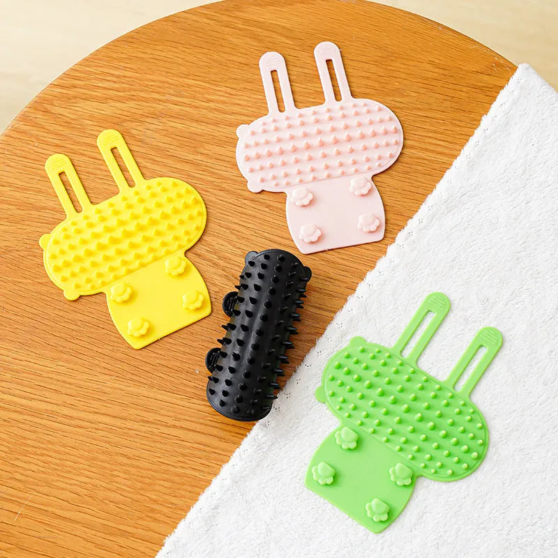 Silicone cat grooming comb with adjustable strap fastened to a table leg for self-cleaning