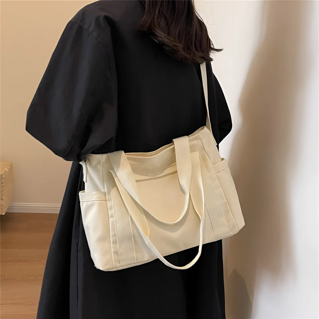 Large black polyester canvas shoulder tote bag showing outer sandwich pocket.