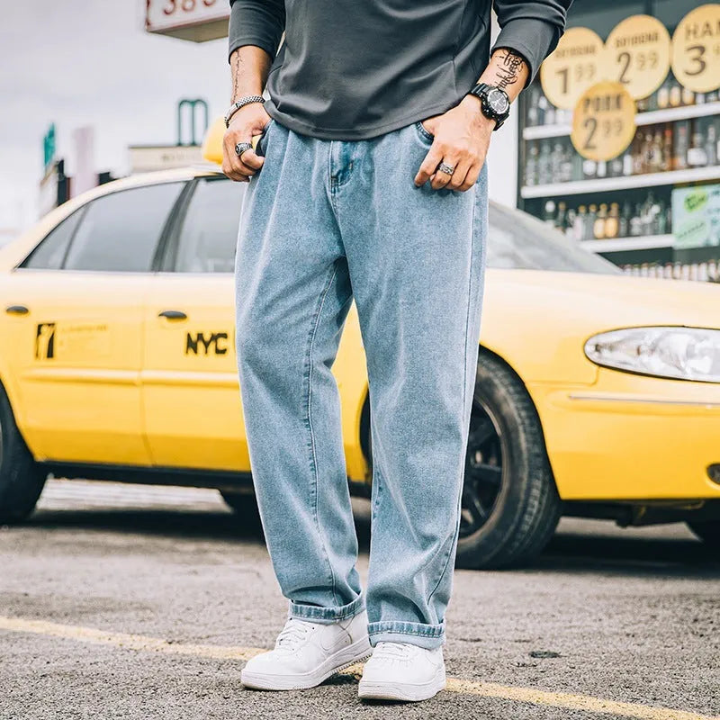 Man wearing loose straight-leg casual jeans in dark blue cotton fabric.