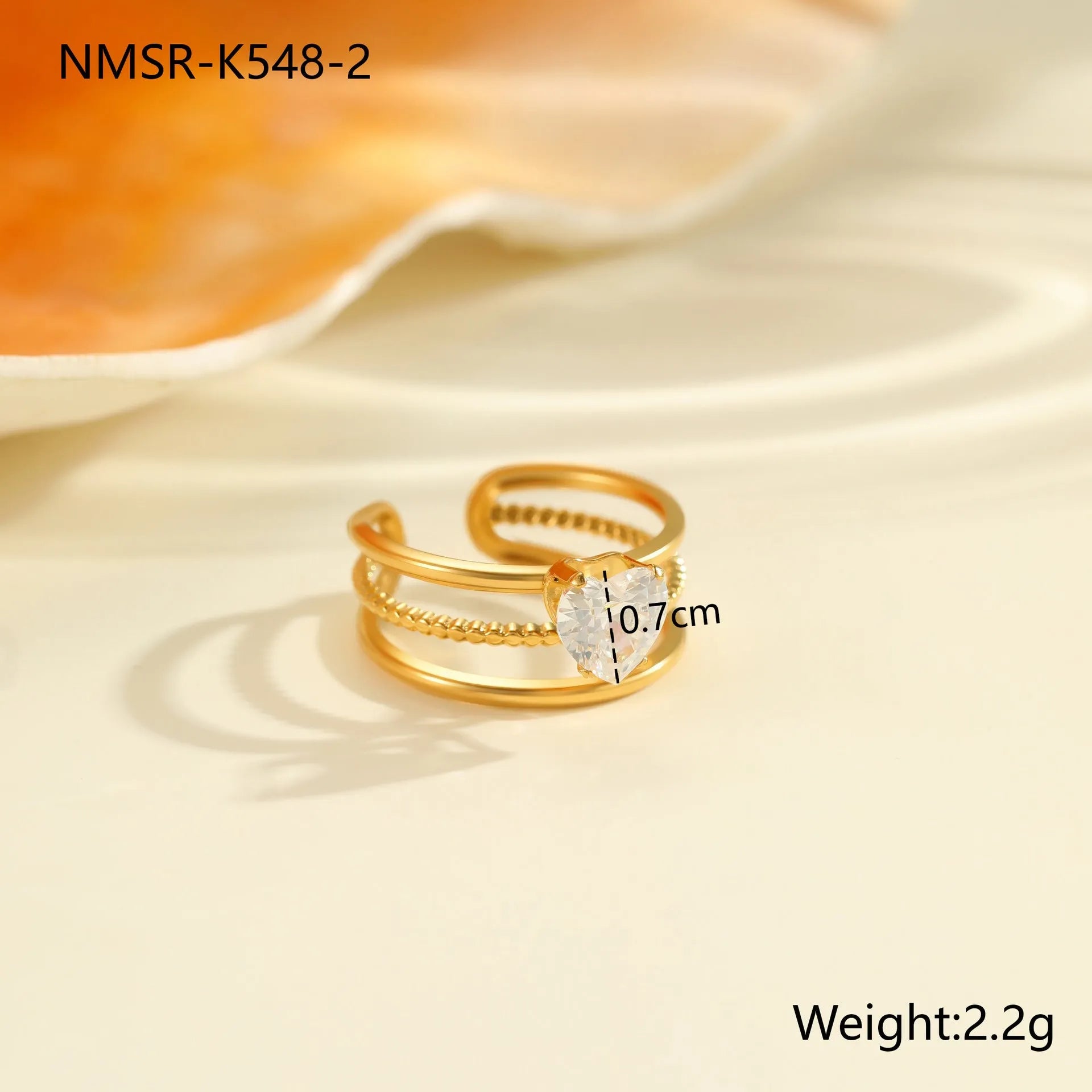 Gold inlaid zircon geometric heart and drop shape stainless steel ring on white background.