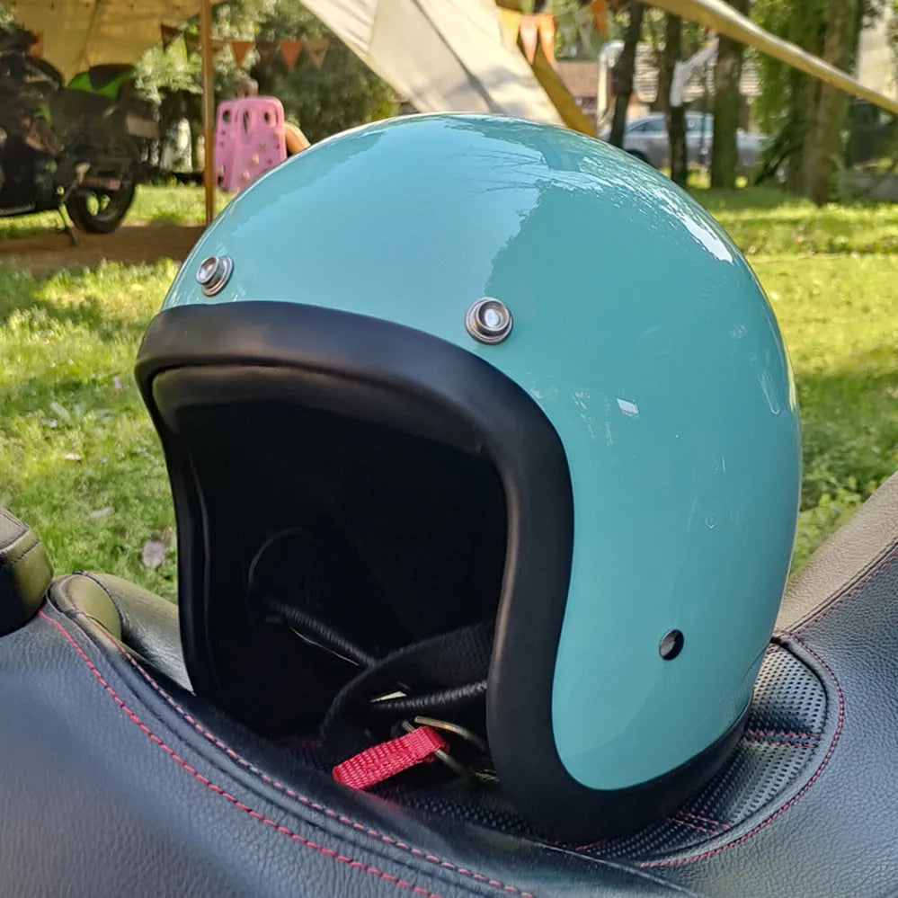 A cement grey retro-style motorcycle half helmet with a floral pattern on the side, showing its open-face design.