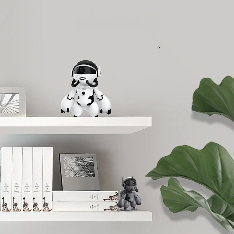 White or black wireless indoor security camera with a detachable base, shown on a shelf for home monitoring.