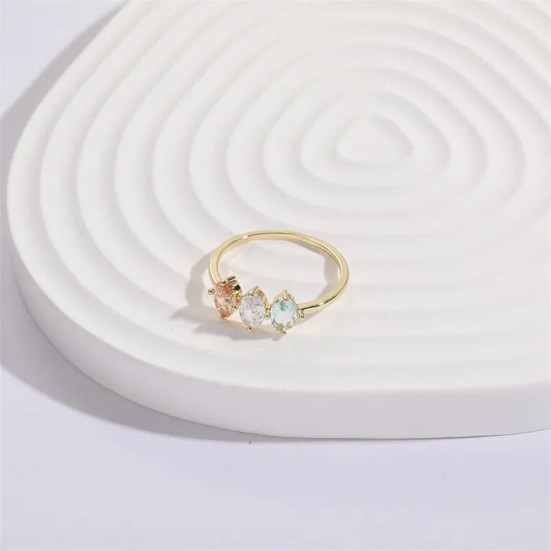 Gold geometric women's ring with horse eye design and three coloured zircon stones on a triangular band.