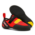 Beginner rock climbing shoes with Velcro strap in black and red colour scheme on a rocky surface.