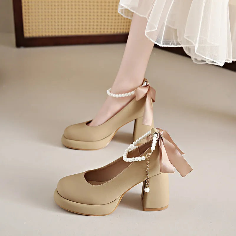 Women's beige Mary Jane shoes with a chunky heel and an ankle-strap buckle on a round toe.